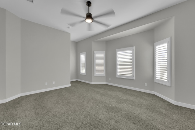 unfurnished room with dark carpet, baseboards, and a ceiling fan