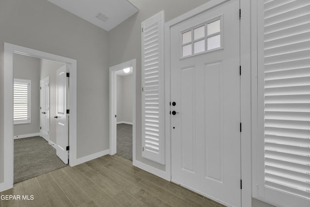 foyer entrance featuring visible vents, baseboards, and wood finished floors