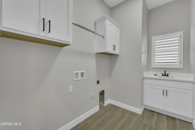 washroom featuring wood finish floors, hookup for a gas dryer, cabinet space, hookup for an electric dryer, and a sink