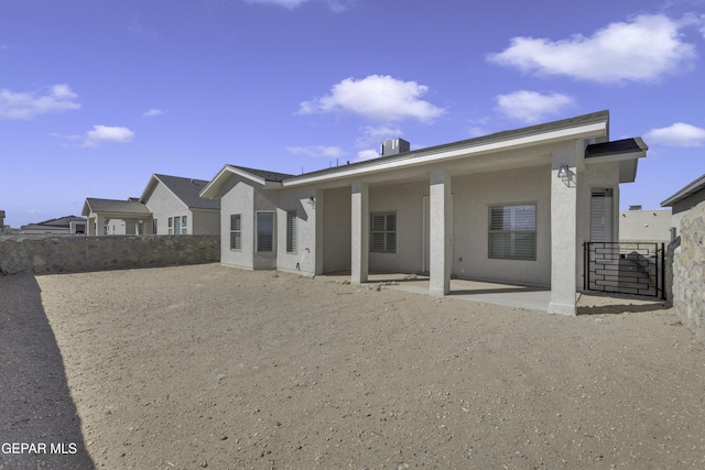 rear view of house featuring stucco siding, a patio, and fence