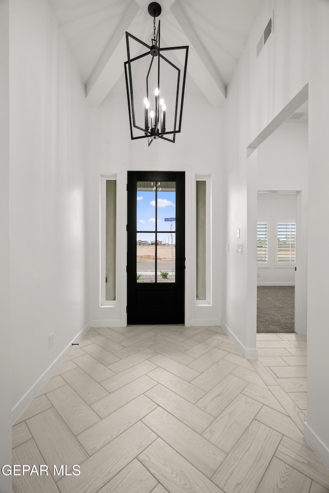 foyer with baseboards, visible vents, a chandelier, and high vaulted ceiling