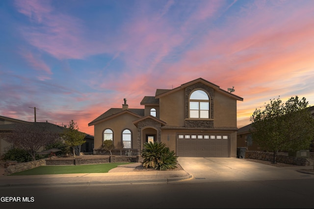 traditional-style home featuring stone siding, stucco siding, driveway, and a garage