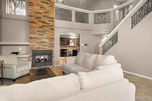 living room with stairway, baseboards, visible vents, a high ceiling, and a multi sided fireplace