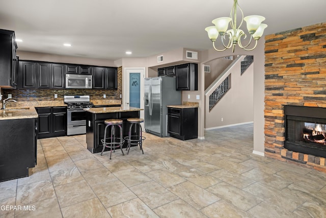 kitchen with visible vents, dark cabinetry, a center island, stainless steel appliances, and a fireplace