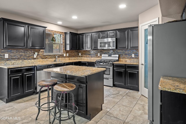 kitchen with appliances with stainless steel finishes, dark cabinetry, and a center island