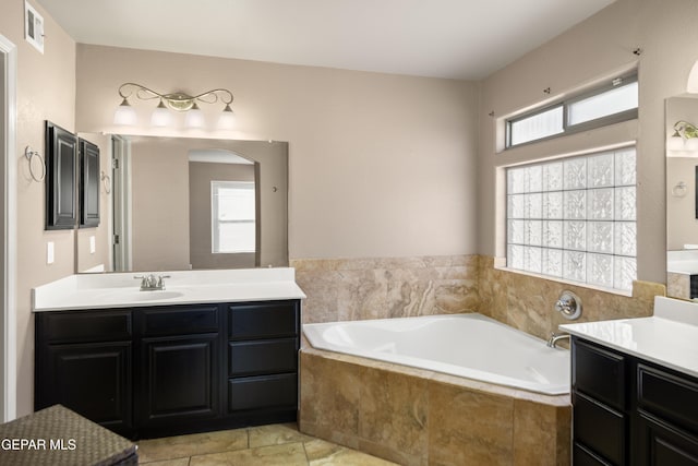 bathroom with two vanities, a bath, visible vents, and a sink