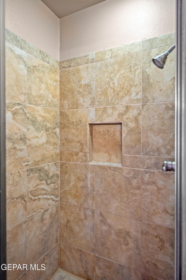 bathroom with tiled shower and a textured wall