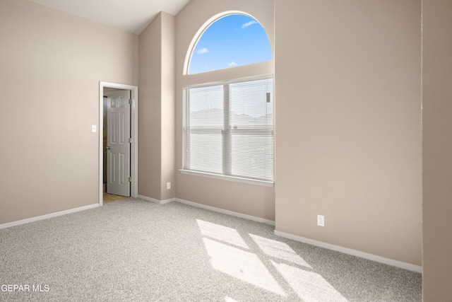 unfurnished room featuring light colored carpet, high vaulted ceiling, and baseboards