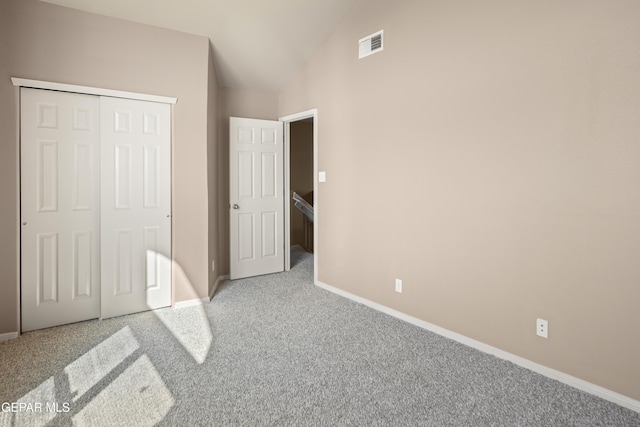 carpeted bedroom featuring baseboards, a closet, lofted ceiling, and visible vents