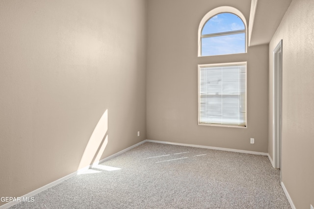 carpeted empty room featuring a wealth of natural light and baseboards