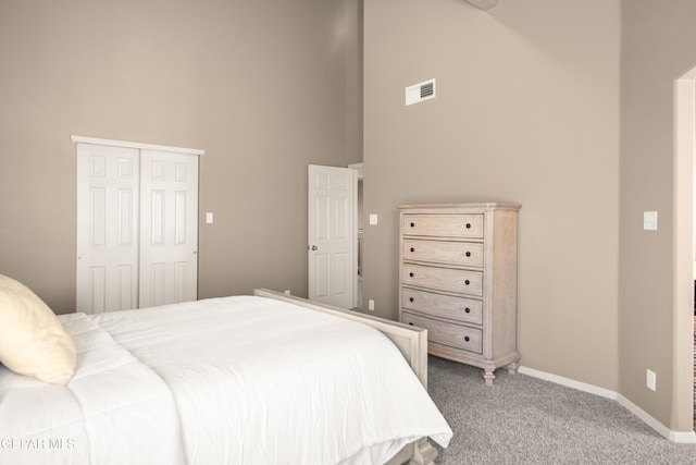 bedroom featuring visible vents, baseboards, a high ceiling, a closet, and light colored carpet