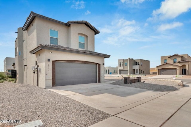 view of front facade with stucco siding, a tiled roof, concrete driveway, and a garage