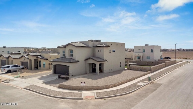 pueblo-style house with stucco siding, a residential view, concrete driveway, a garage, and a tiled roof