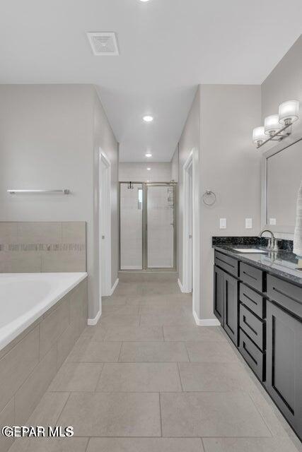 full bathroom with visible vents, a garden tub, a stall shower, baseboards, and vanity