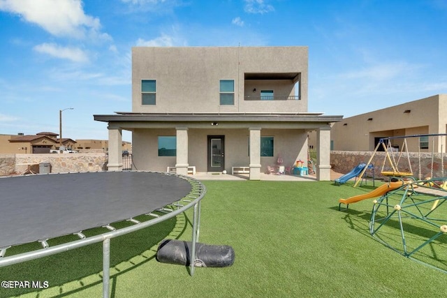 back of property with stucco siding, playground community, a patio, and fence