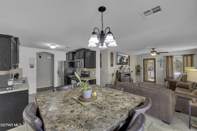 dining room with visible vents, arched walkways, baseboards, and ceiling fan with notable chandelier