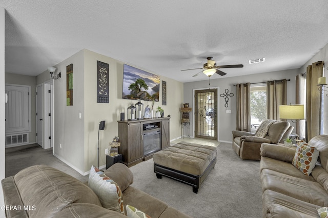 living room with a textured ceiling, visible vents, carpet floors, and ceiling fan