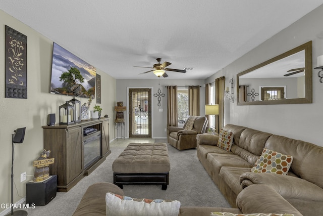 living room featuring baseboards, light carpet, ceiling fan, and a fireplace