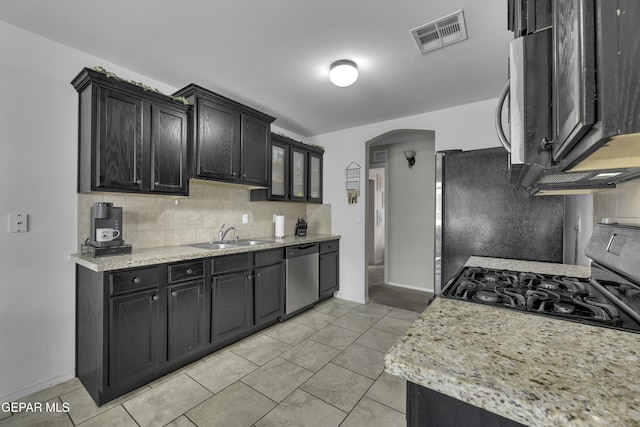 kitchen featuring visible vents, dark cabinetry, arched walkways, stainless steel appliances, and a sink