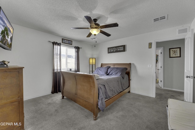 bedroom featuring visible vents, a textured ceiling, carpet, and a ceiling fan