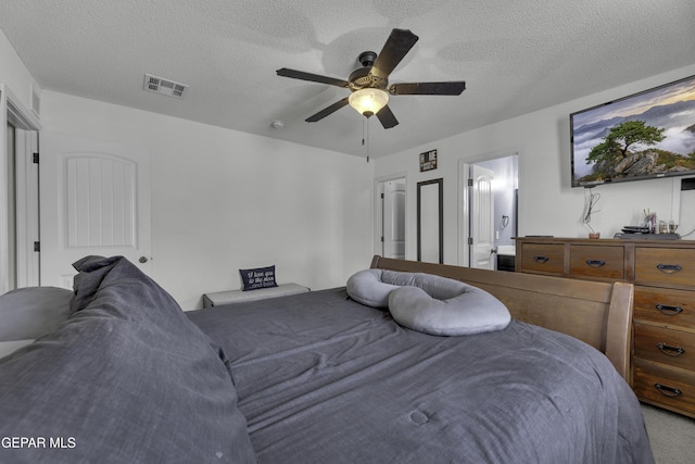 bedroom with ceiling fan, visible vents, carpet floors, and a textured ceiling