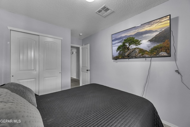 bedroom featuring visible vents, a textured ceiling, and a closet