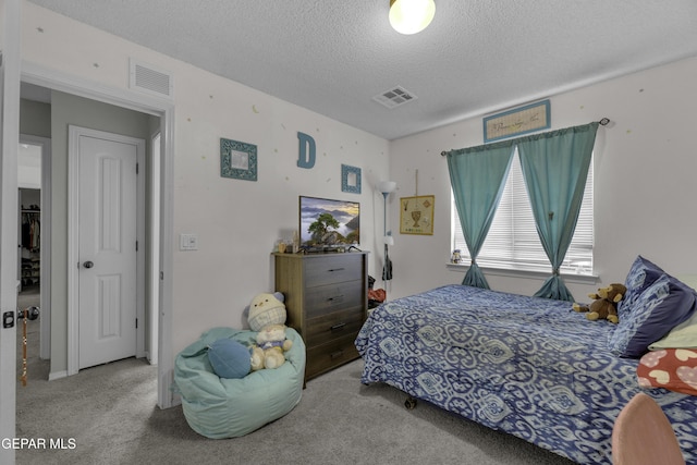 bedroom with visible vents, a textured ceiling, and carpet floors