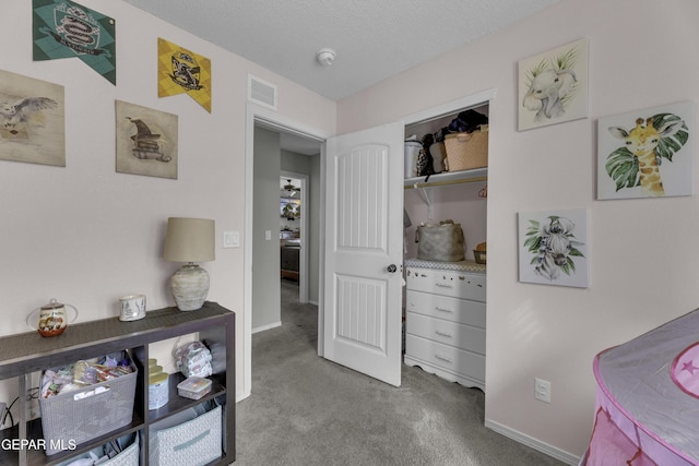 hallway featuring visible vents, a textured ceiling, baseboards, and carpet floors