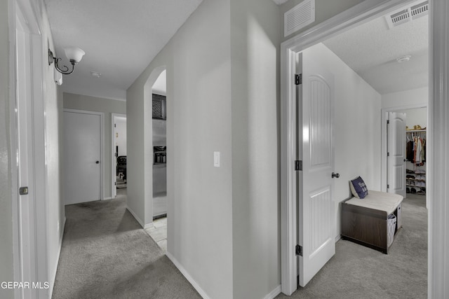 corridor featuring visible vents, arched walkways, and light colored carpet