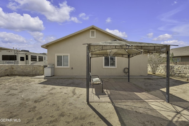 rear view of house featuring a gazebo, stucco siding, and a patio area