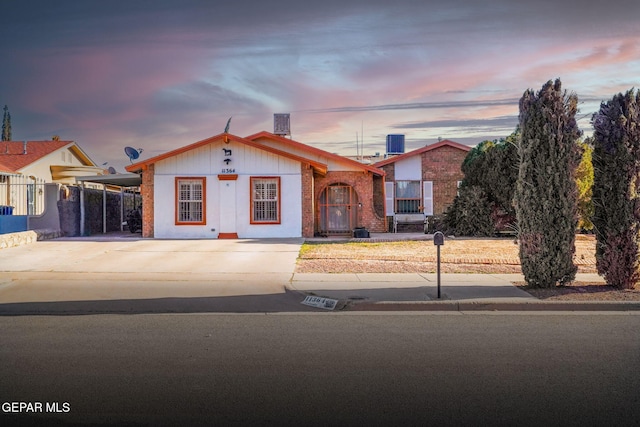 view of front of property featuring central air condition unit, an attached carport, concrete driveway, and brick siding