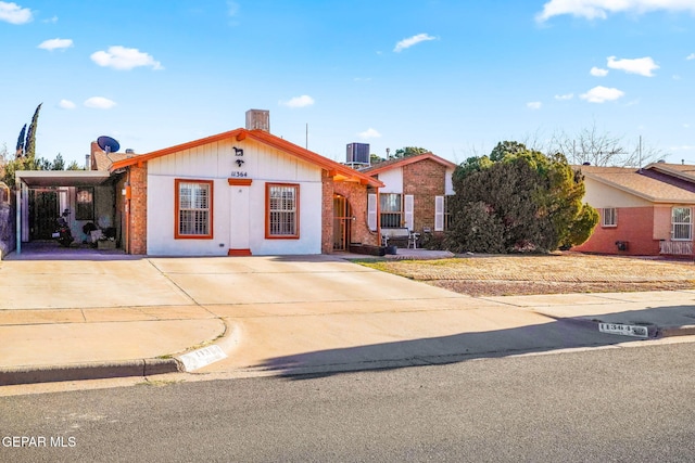 ranch-style home with brick siding, cooling unit, an attached carport, and driveway