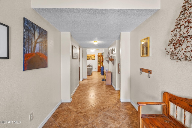 hallway featuring light tile patterned flooring, baseboards, and a textured ceiling