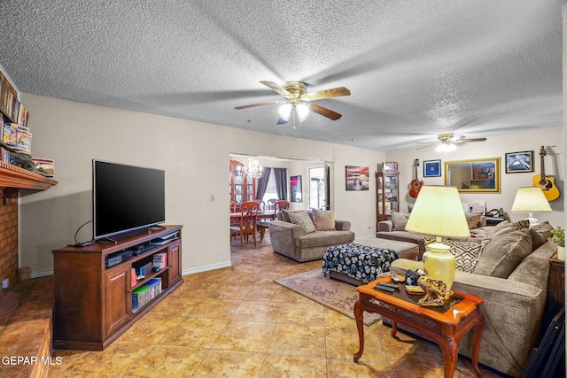 living area with light tile patterned floors, baseboards, a textured ceiling, and ceiling fan with notable chandelier