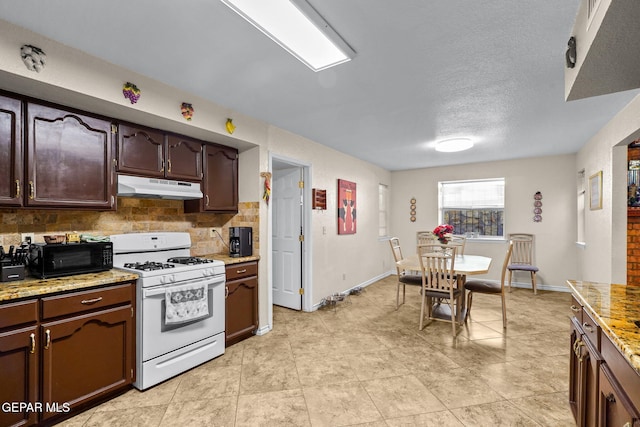 kitchen with under cabinet range hood, backsplash, a textured ceiling, baseboards, and white range with gas stovetop