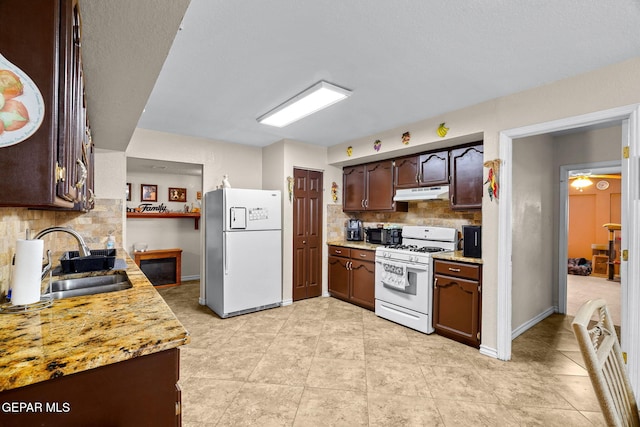 kitchen with white appliances, light countertops, under cabinet range hood, and a sink