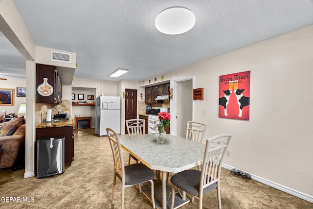 dining area featuring baseboards, visible vents, and a textured ceiling