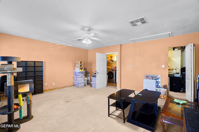 office with visible vents, carpet, attic access, washer / clothes dryer, and a ceiling fan