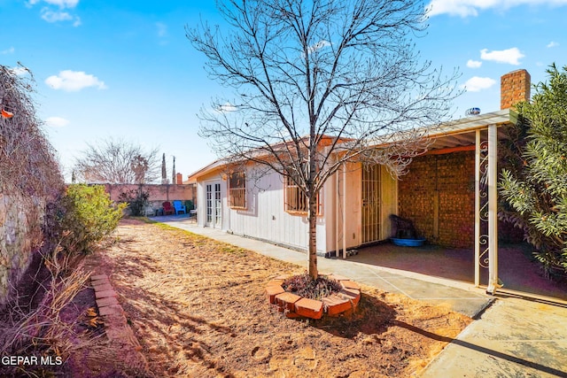 view of property exterior with a chimney and fence