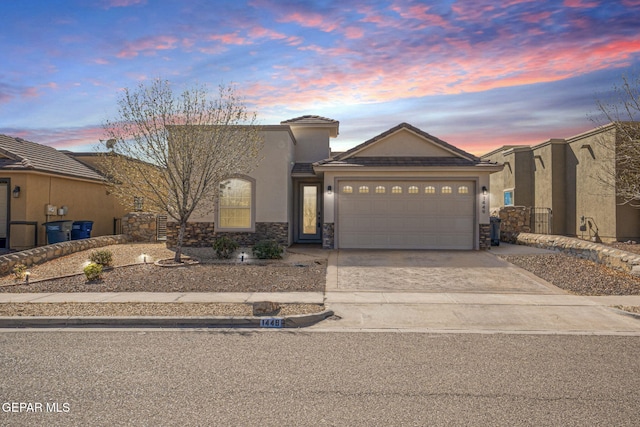 view of front of home with stucco siding, driveway, a tile roof, stone siding, and an attached garage