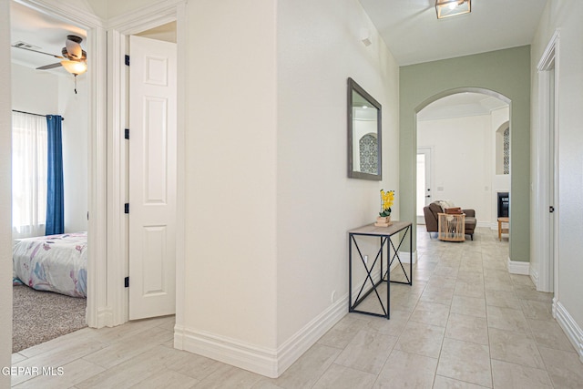 corridor with baseboards and arched walkways