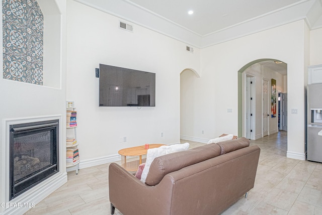 living room with arched walkways, visible vents, a fireplace, and baseboards