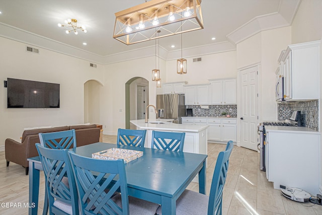 dining room featuring arched walkways, visible vents, crown molding, and a high ceiling