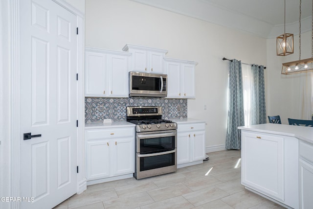 kitchen featuring tasteful backsplash, pendant lighting, light countertops, appliances with stainless steel finishes, and white cabinetry