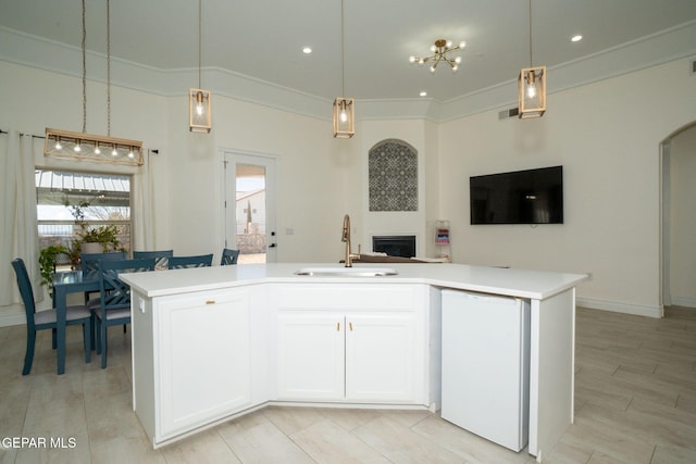 kitchen with an island with sink, a sink, decorative light fixtures, open floor plan, and light countertops