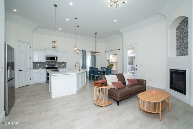 living area with a glass covered fireplace, an inviting chandelier, a high ceiling, and ornamental molding