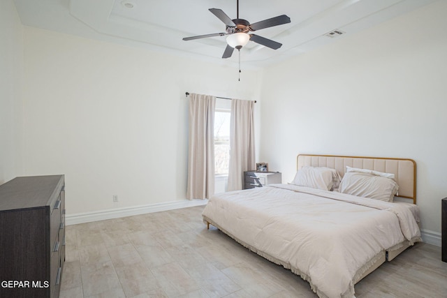 bedroom with visible vents, a raised ceiling, baseboards, and a ceiling fan