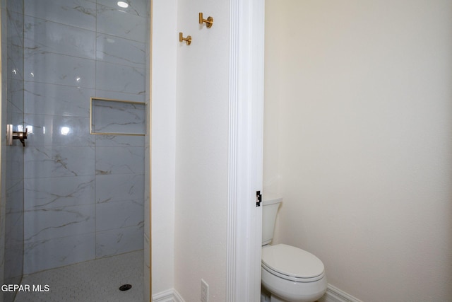 full bath featuring toilet, baseboards, and a marble finish shower