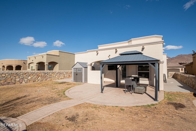 exterior space with stucco siding, an outbuilding, a gazebo, a storage shed, and a patio area