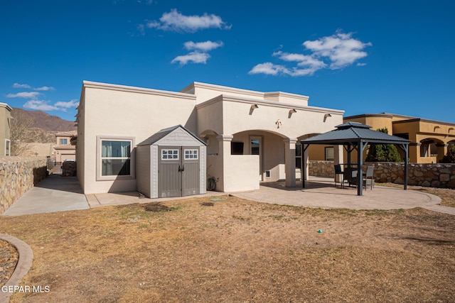 back of house with a patio, a shed, stucco siding, a gazebo, and an outdoor structure